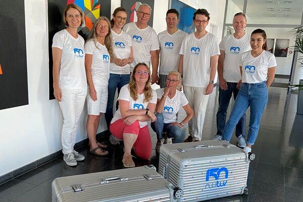 Mitarbeiter von Tochterunternehmen der RWTÜV Gruppe mit dem Jubiläumskoffer